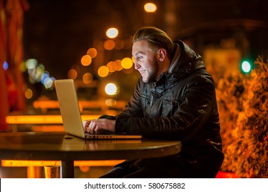 handsome young man with a computer on the street at night - Shutterstock ID 580675882