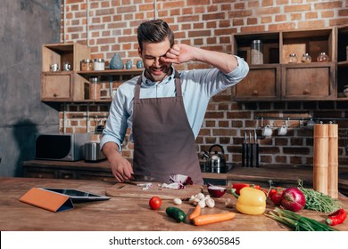 handsome young man crying while cutting onion - Powered by Shutterstock