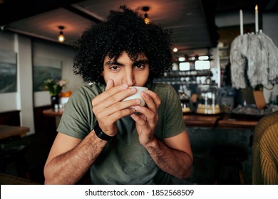 Handsome Young Man With Curly Hair Sipping Hot Coffee Relaxing In Cafe