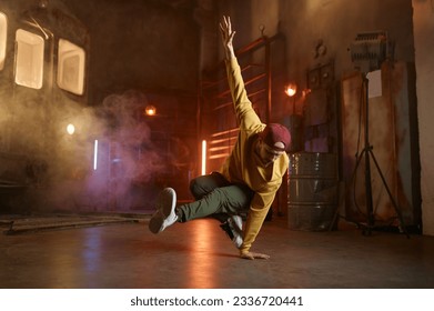 Handsome young man dancing movements over urban studio background