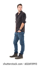 Handsome Young Man In Dark Grayish Plaid Shirt Looking Back Over Shoulder. Full Body Length Portrait Isolated Over White Studio Background. 