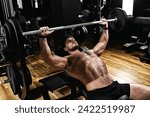 handsome young man doing bench press workout in gym, Fitness motivation, sports lifestyle, health, athletic body, body positive. Film grain, selective focus