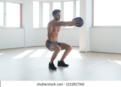 Handsome Young Man Doing Squad With Medicine Ball As Part Of Bodybuilding Training - Shutterstock ID 1212817342