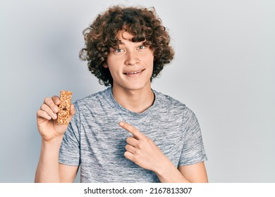 Handsome Young Man Eating Protein Bar As Healthy Energy Snack Smiling Happy Pointing With Hand And Finger 