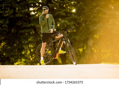 Handsome young man with ebike, mountain bike with electric battery in the park