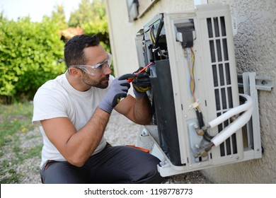 handsome young man electrician installing an air conditioning in a client house