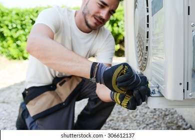 handsome young man electrician installing air conditioning in a client house 