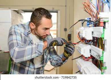 handsome young man electrician working on switchboard of house building construction site 