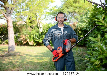 Similar – Image, Stock Photo Gardener trimming a hedgerow using a hedge trimmer in the garden of a customer with earmuffs on for protection