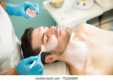 Handsome young man getting a facial treatment and an anti-aging mask in a health spa