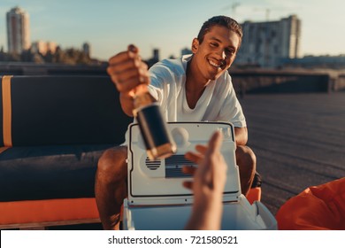 Handsome Young Man Giving Beer Bottle From Portable Fridge