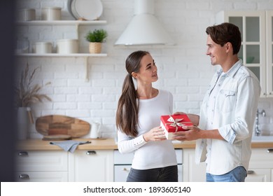 Handsome Young Man Giving Present To Beautiful Woman At Home. Happy Family Concept.