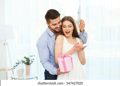 Handsome Young Man Giving Present To Beautiful Woman At Home