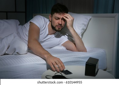 Handsome Young Man Going To Take Pills Against Headache While Lying In Bed At Night