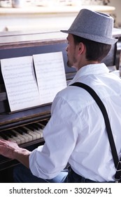 Handsome Young Man In Hat Making Piano Music, Back View