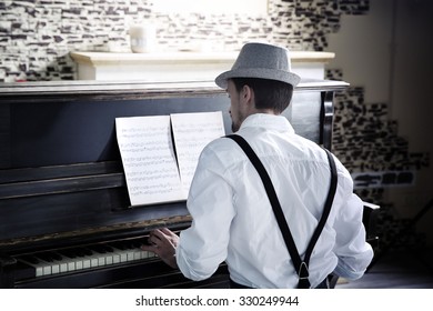 Handsome Young Man In Hat Making Piano Music, Back View