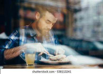 Handsome young man having lunch in elegant restaurant alone. Somebody is looking at him from street through the window. Person can see guy is happy to have such great meal - Powered by Shutterstock