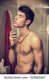 Handsome Young Man In His Home Bathroom, Spraying Cologne Or Perfume On Neck