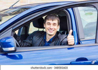 Handsome young man with his thumb up sitting in his new car  - Shutterstock ID 348581603