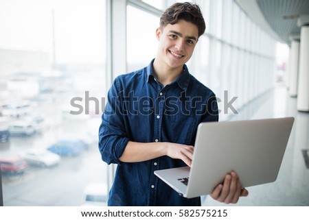Handsome young man man holding a laptop in hall