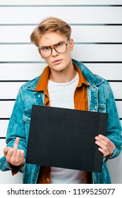 Handsome Young Man Holding Prison Board While Standing In Front Of Police Line Up