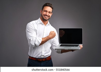 A Handsome Young Man Holding And Showing The Screen Of A Laptop And Celebrating
