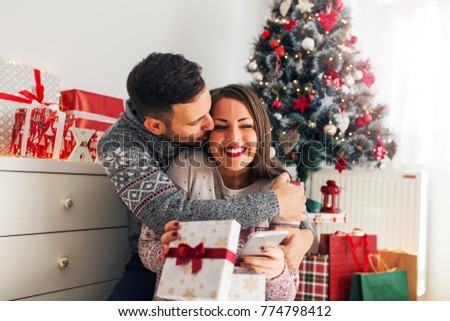 Handsome young man hugging and surprising his girlfriend for Christmas