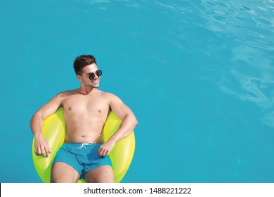 Handsome Young Man With Inflatable Ring In Swimming Pool On Sunny Day, Above View. Space For Text