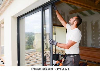 ansehnlicher junger Mann, der eine Fensterfront auf einer neuen Baustelle installiert