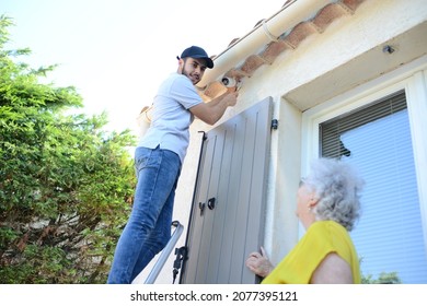 Handsome Young Man Installing House Security Anti Burglary Camera And Siren Alarm In A Senior Woman Home