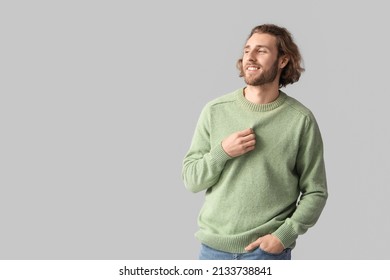 Handsome young man in knitted sweater on grey background - Shutterstock ID 2133738841