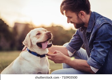 Handsome Young Man With Labrador Outdoors. Man On A Green Grass With Dog Labrador Retriever.