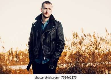 Handsome Young Man In Leather Jacket In The Autumn Park On A Sunset. Seasonal Fashion.