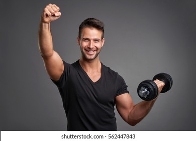 A handsome young man lifting weight smiling and raising his fist 
 - Powered by Shutterstock