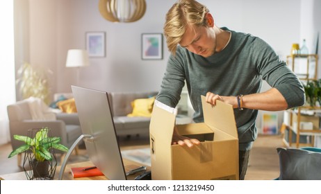 Handsome Young Man In Living Room With Cardboard Box Package, Opening It With Interest.