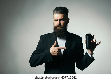 Handsome Young Man With Long Beard And Moustache In Black Jacket Holding Tin Beer Can Bottle In Studio On Grey Background