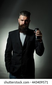 Handsome Young Man With Long Beard And Moustache In Black Jacket Holding Tin Beer Can Bottle In Studio On Grey Background