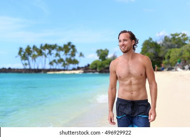 Handsome Young Man Looking Away On Summer Beach Vacation. Portrait Of An Attractive Caucasian Male Model With Fit Body And Sexy Abs In Swim Trunks Relaxing On A Tropical Travel Destination.