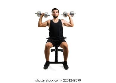 Handsome young man looking at the camera while lifting dumbbell weights during his fit workout - Powered by Shutterstock