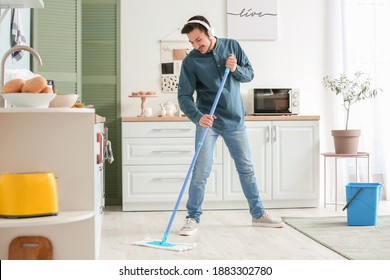 Handsome Young Man Mopping Floor In Kitchen