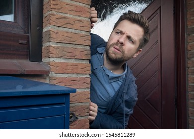 Handsome young man opening door looking on what his neighbor is doing suspecting something.