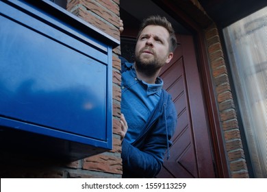 Handsome Young Man Opening Door Looking On What His Neighbor Is Doing Suspecting Something.