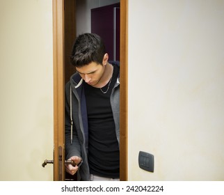 Handsome Young Man Opening Door To Enter Into A Room, Looking Down At Handle