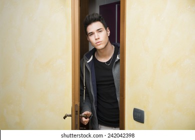 Handsome Young Man Opening Door To Enter Into A Room, Looking At Camera