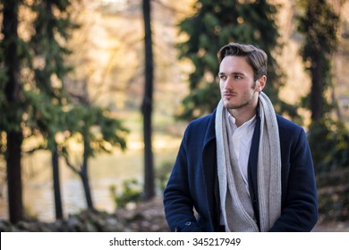 Handsome Young Man Outdoor In Winter Fashion, Wearing Black Coat And Woolen Scarf In City Park