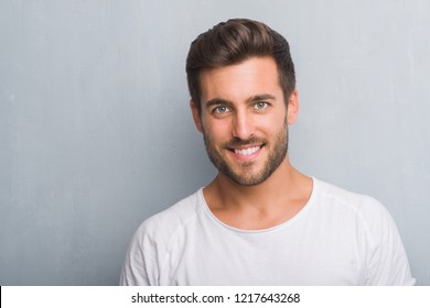 Handsome Young Man Over Grey Grunge Wall With A Happy Face Standing And Smiling With A Confident Smile Showing Teeth