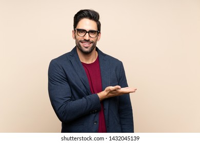 Handsome young man over isolated background presenting an idea while looking smiling towards