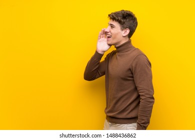 Handsome young man over isolated yellow background shouting with mouth wide open to the lateral - Shutterstock ID 1488436862