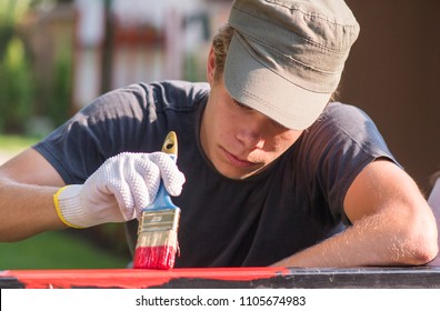 Handsome Young Man Is Painting Metal Fence With A Brush