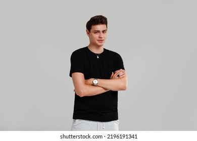 Handsome Young Man Posing In Black Fashionable Shirt, Hand Watch And Jewelry, Looking At The Camera. Student. Studio Shot. Grey Background. Copy Space. 
